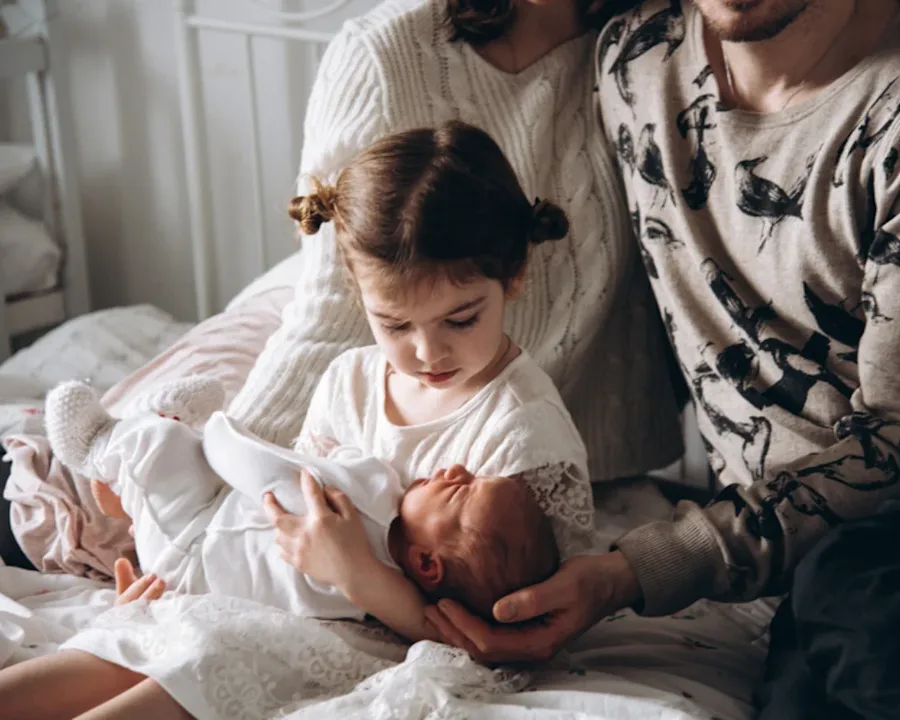 A family seated together with a child holding an infant. 