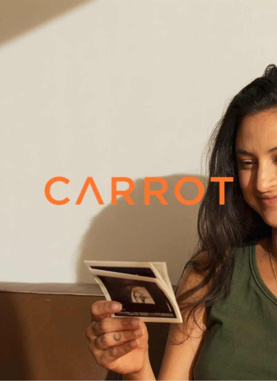 A person smiling while holding images with the Carrot logo.