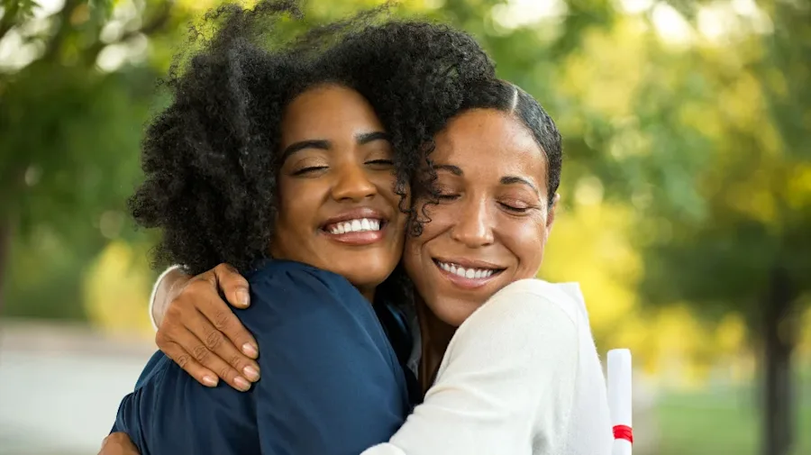 Two women embracing each other, smiling.