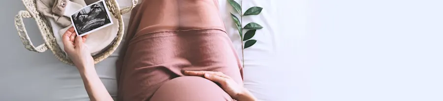 A pregnant person holding an ultrasound image.