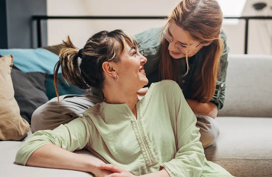 Two women sitting on a couch together.