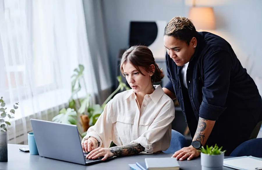 Two people looking at a laptop together reading.