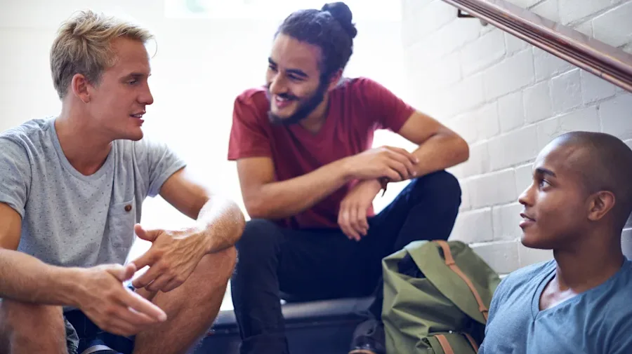 Three men sitting and talking in a stairwell.