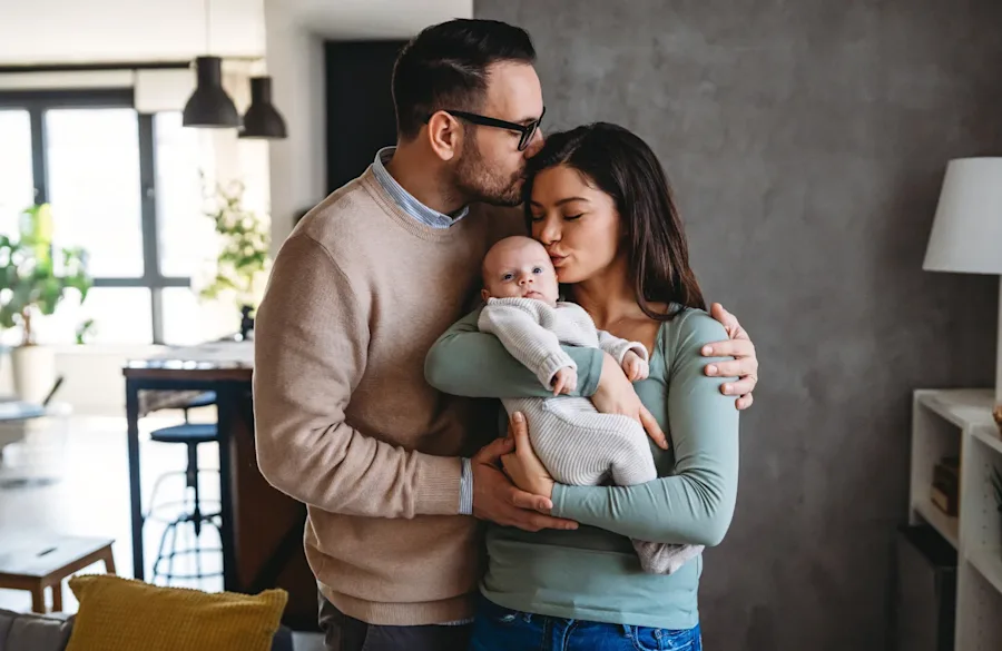 A father kissing a mother on the head as the mother kisses an infant on the head.