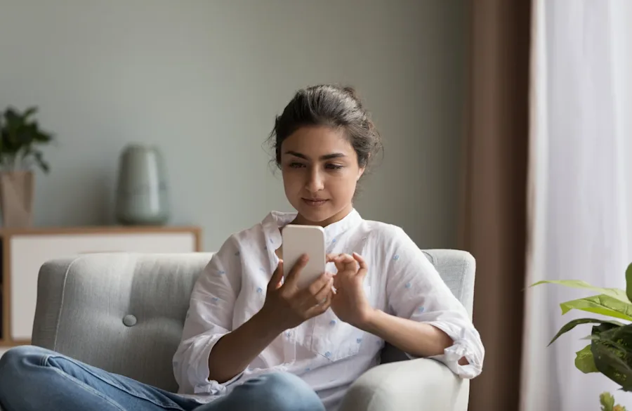 A person seated in a chair interacting with their phone.