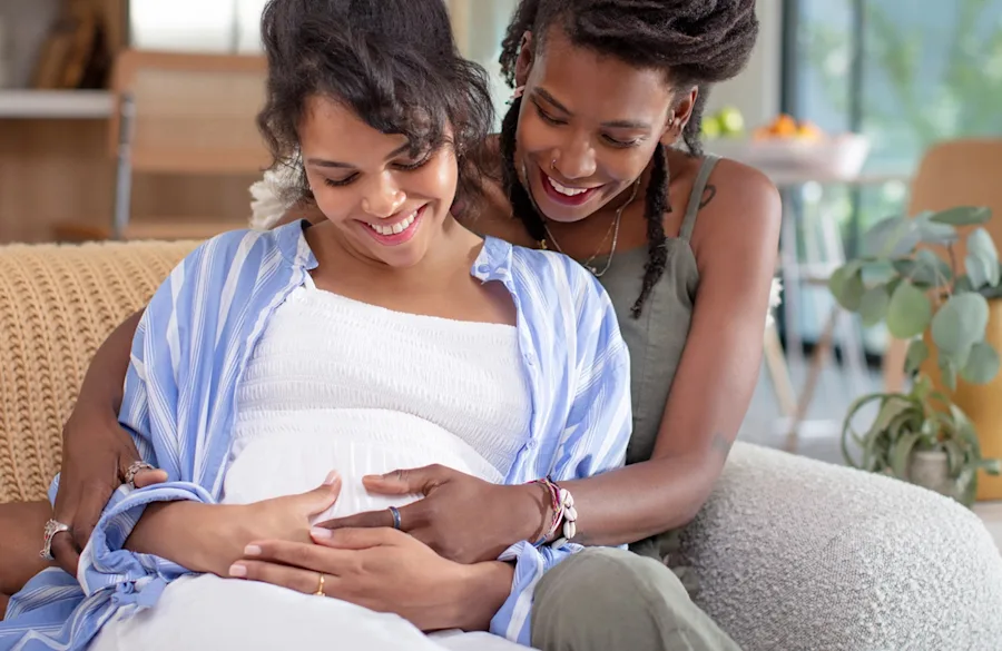Couple sitting on a couch admiring the pregnancy belly.