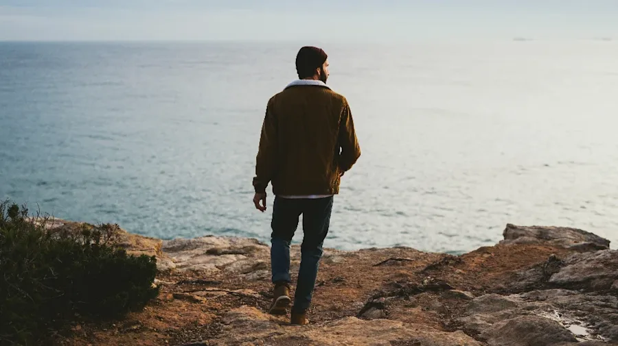 A person walking on rocks near the ocean.