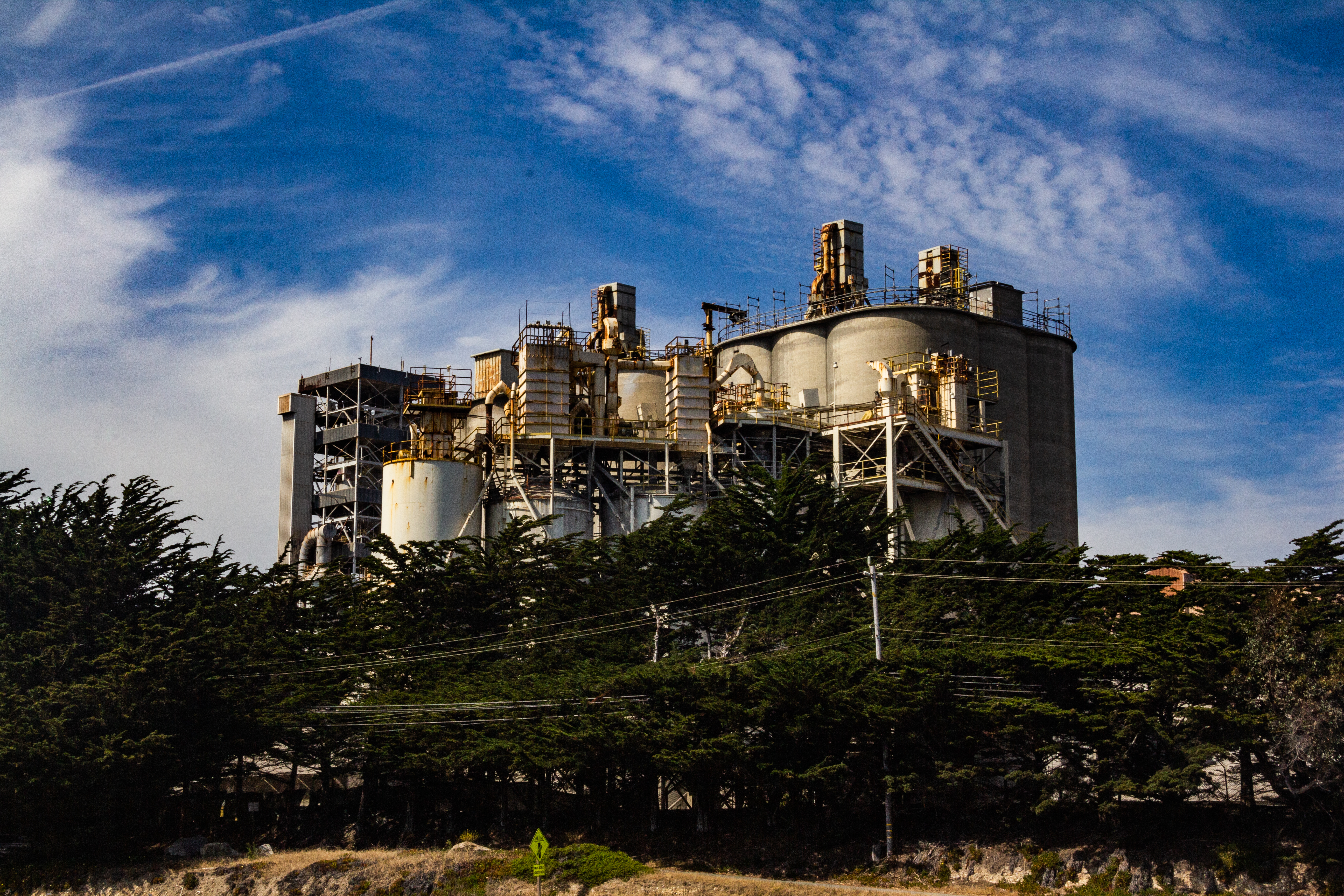 A photograph of an industrial building behind some trees.
