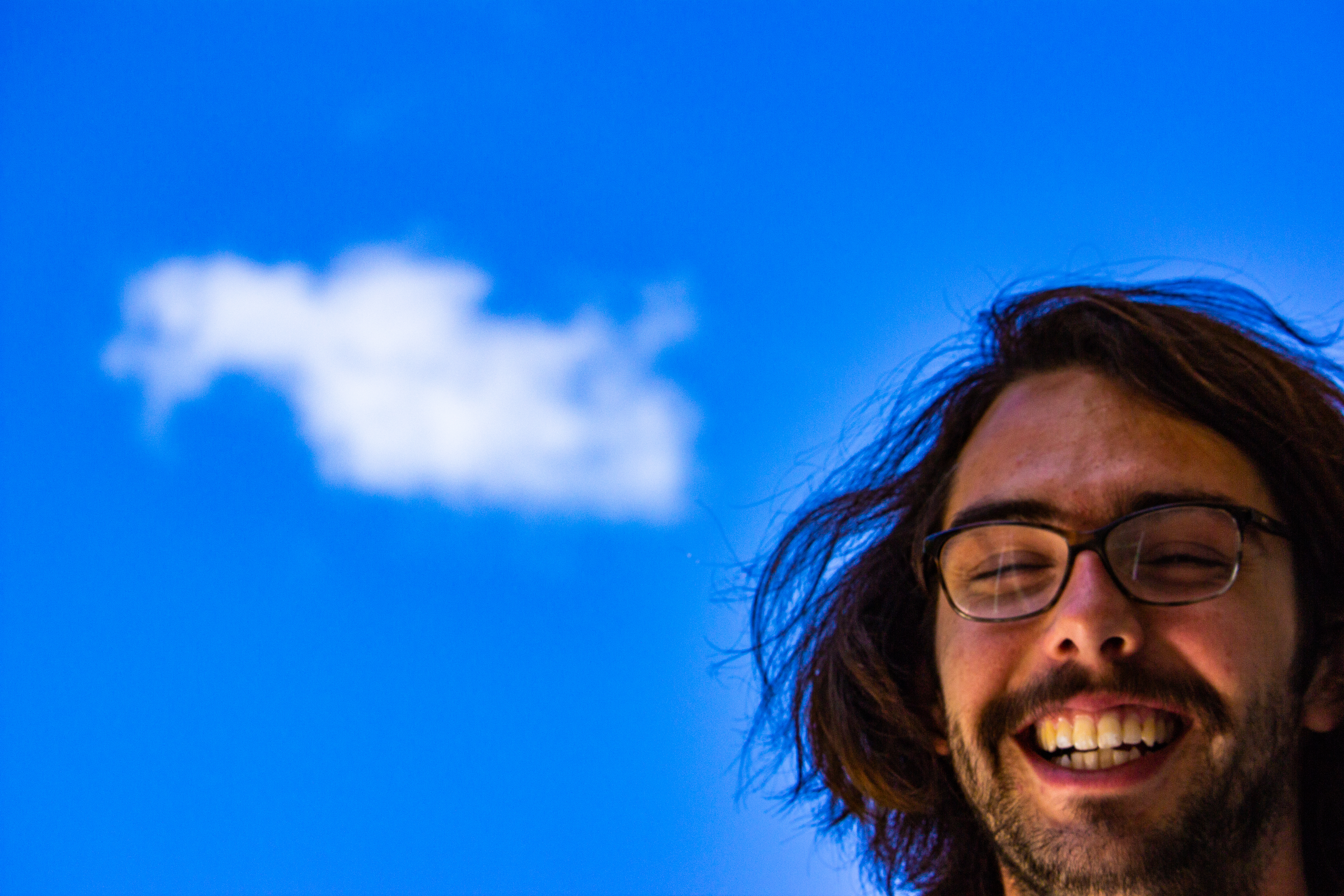 A photograph of a cloud behind a smiling person's face.
