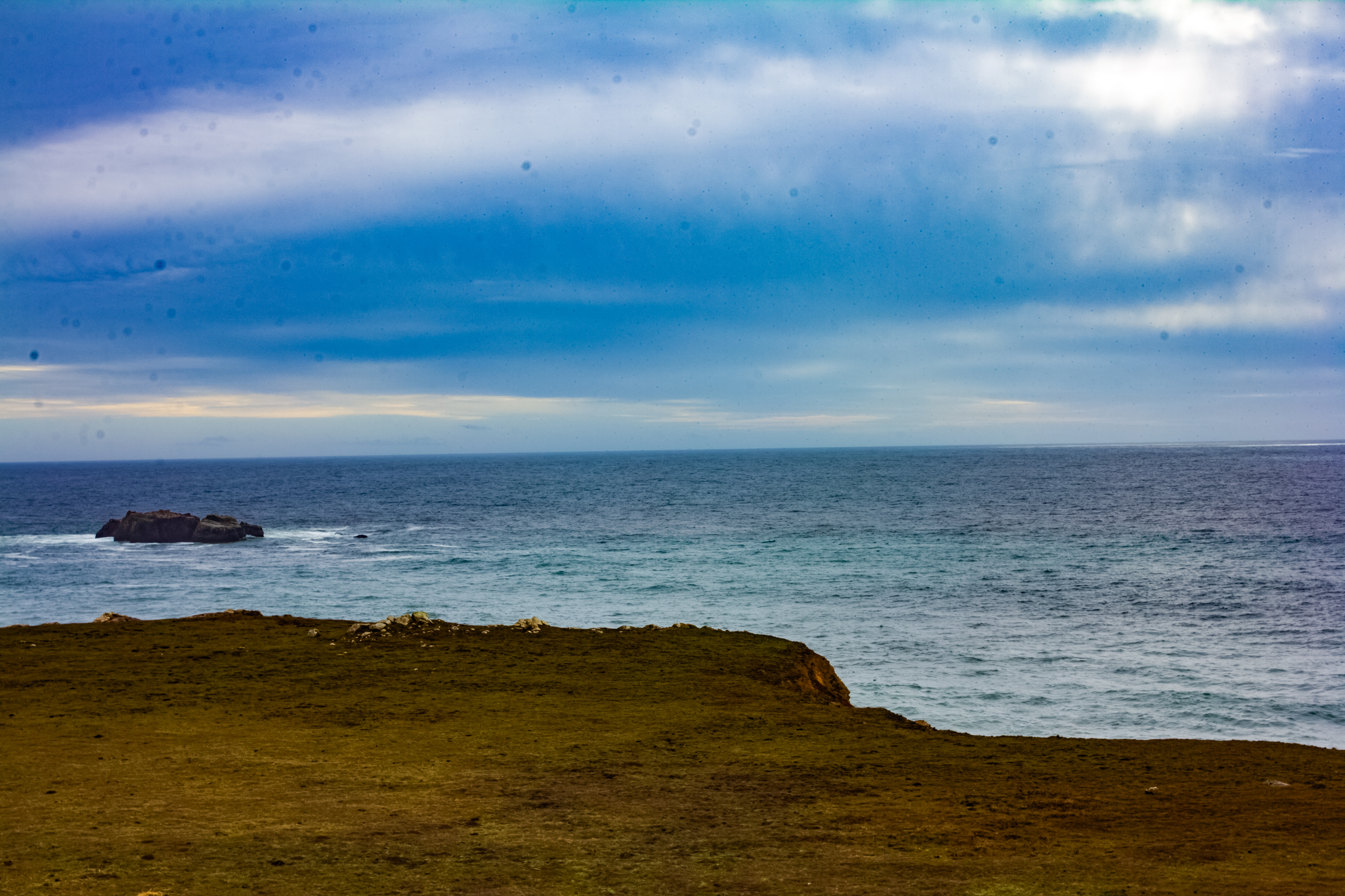 A photograph of a flat grassy plateau looking over the ocean.