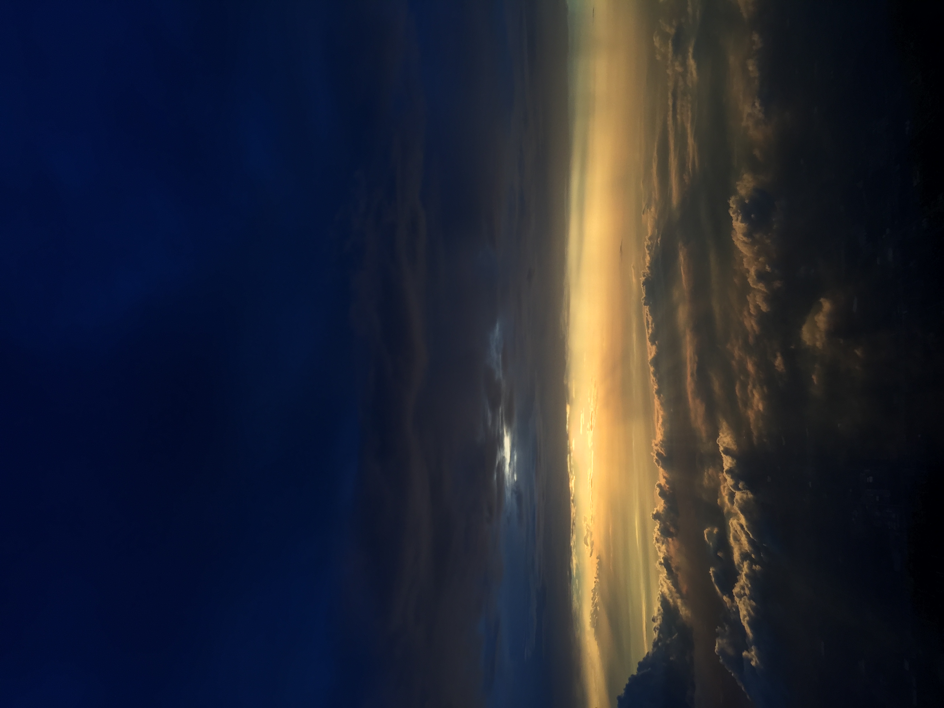 A photograph of the sun illuminating large clouds below the viewer.