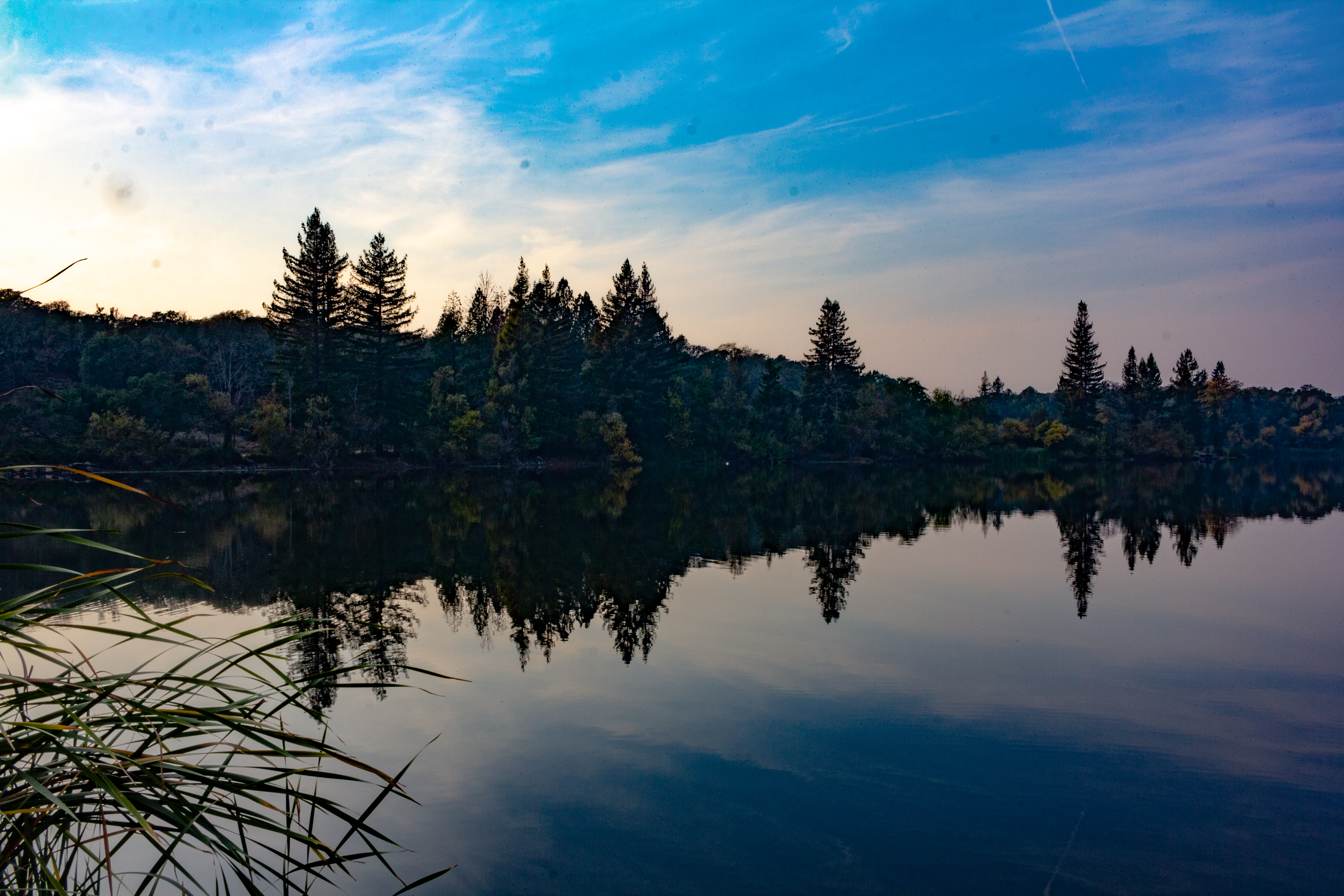 A photograph of a lake, with the shoreline reflected in the water.