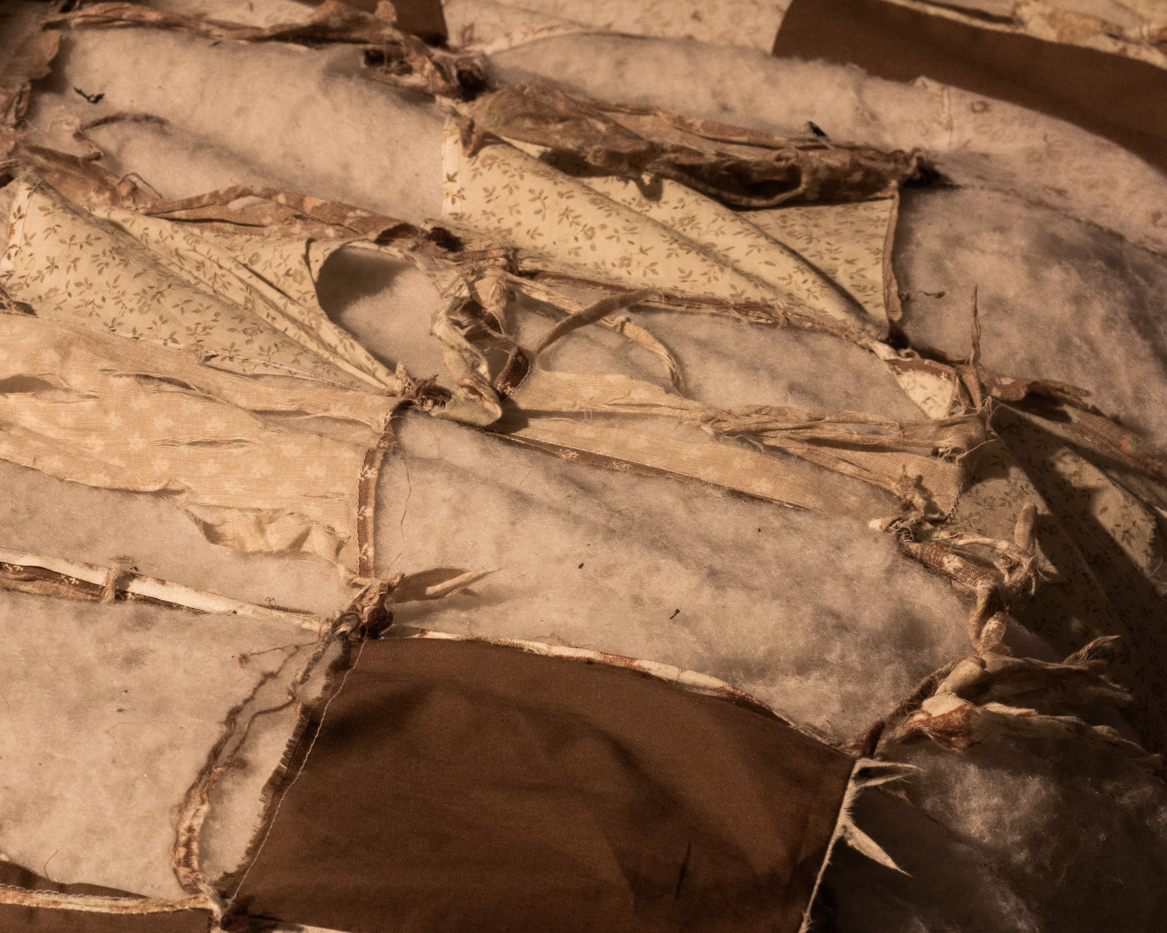 A photograph of a quilt, showing many tears.