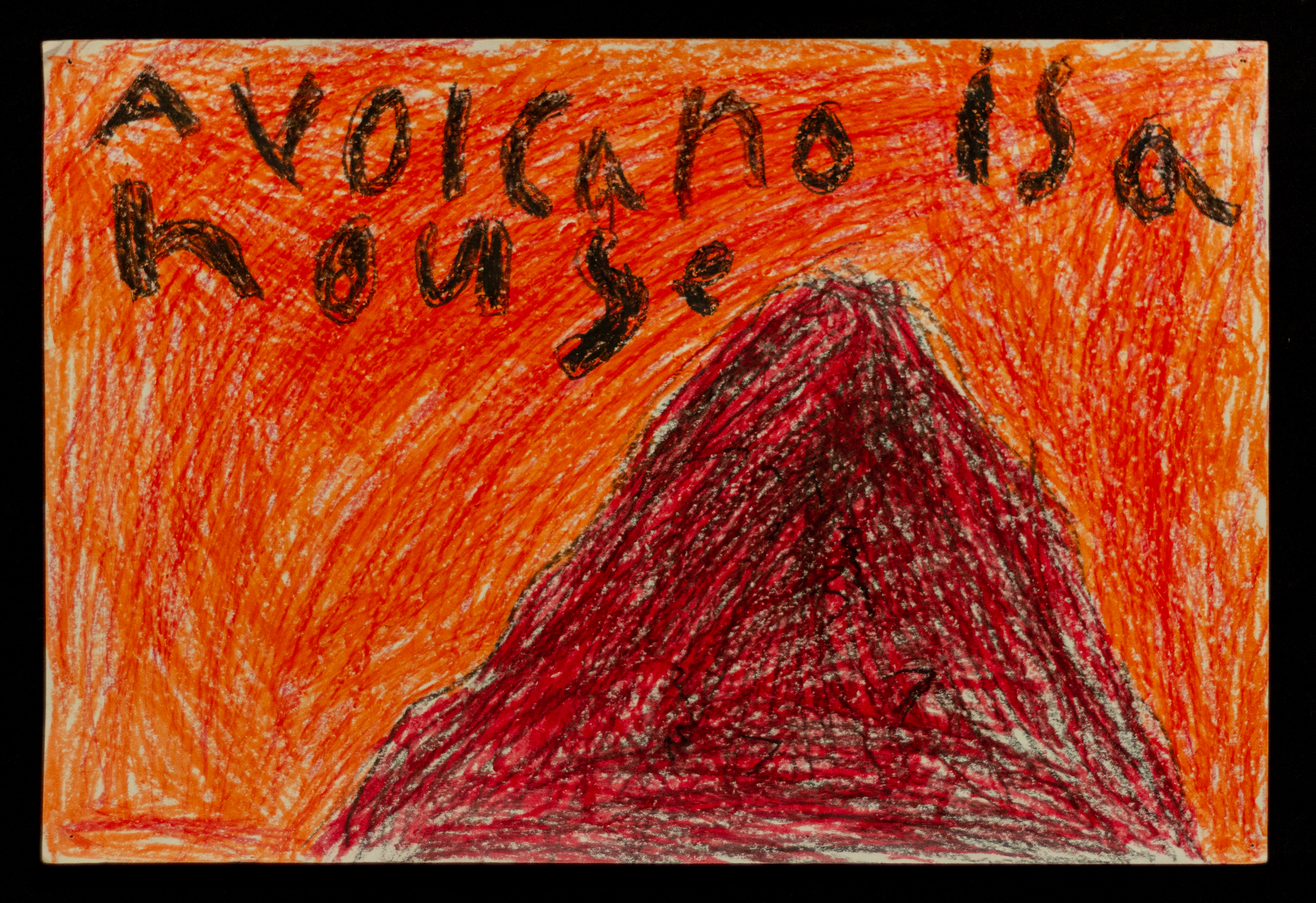 A crayon drawing of a volcano, with the words "A volcano is a house" written above it.