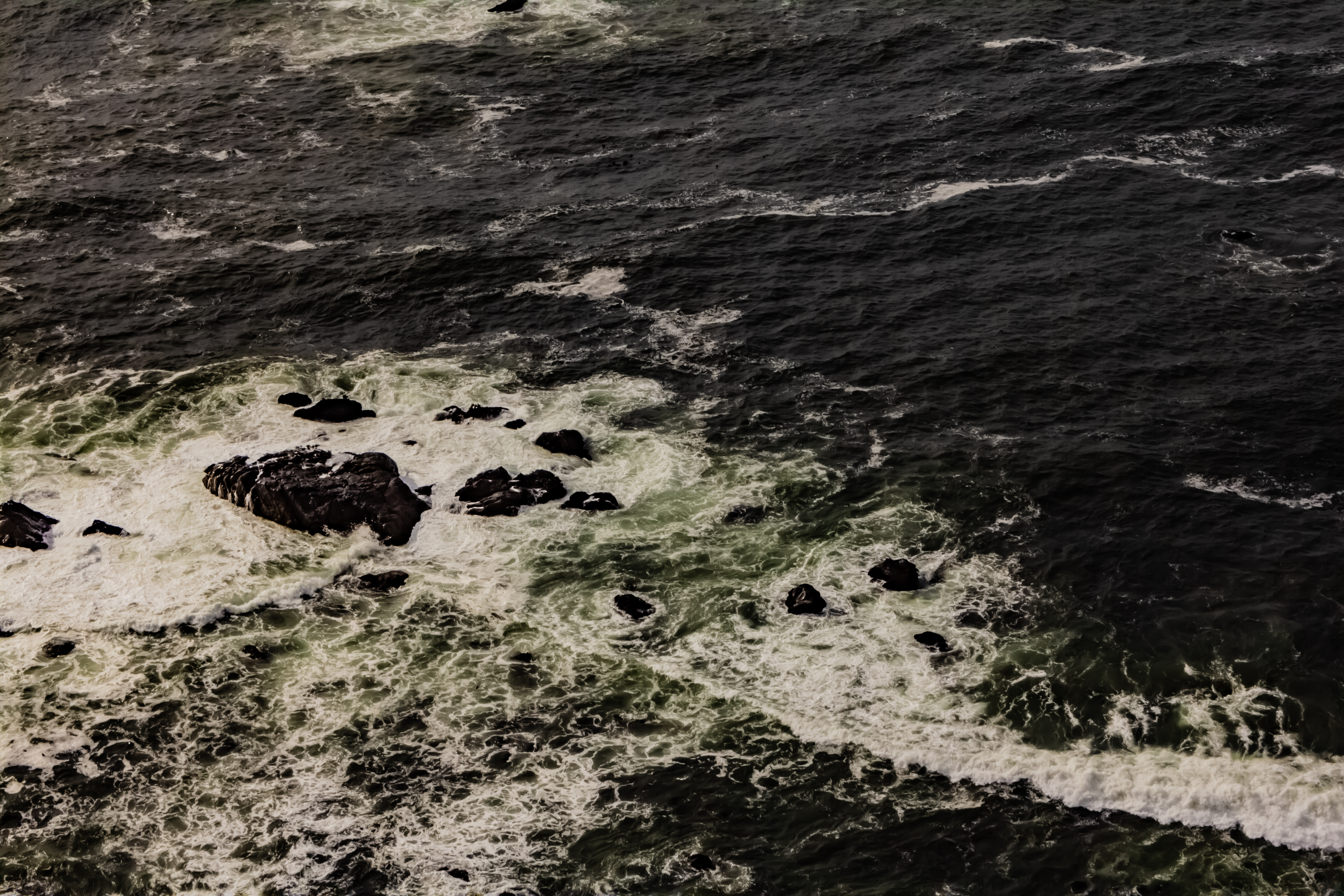 A photograph of the foam that forms between rocks in shallow ocean water near the coast.