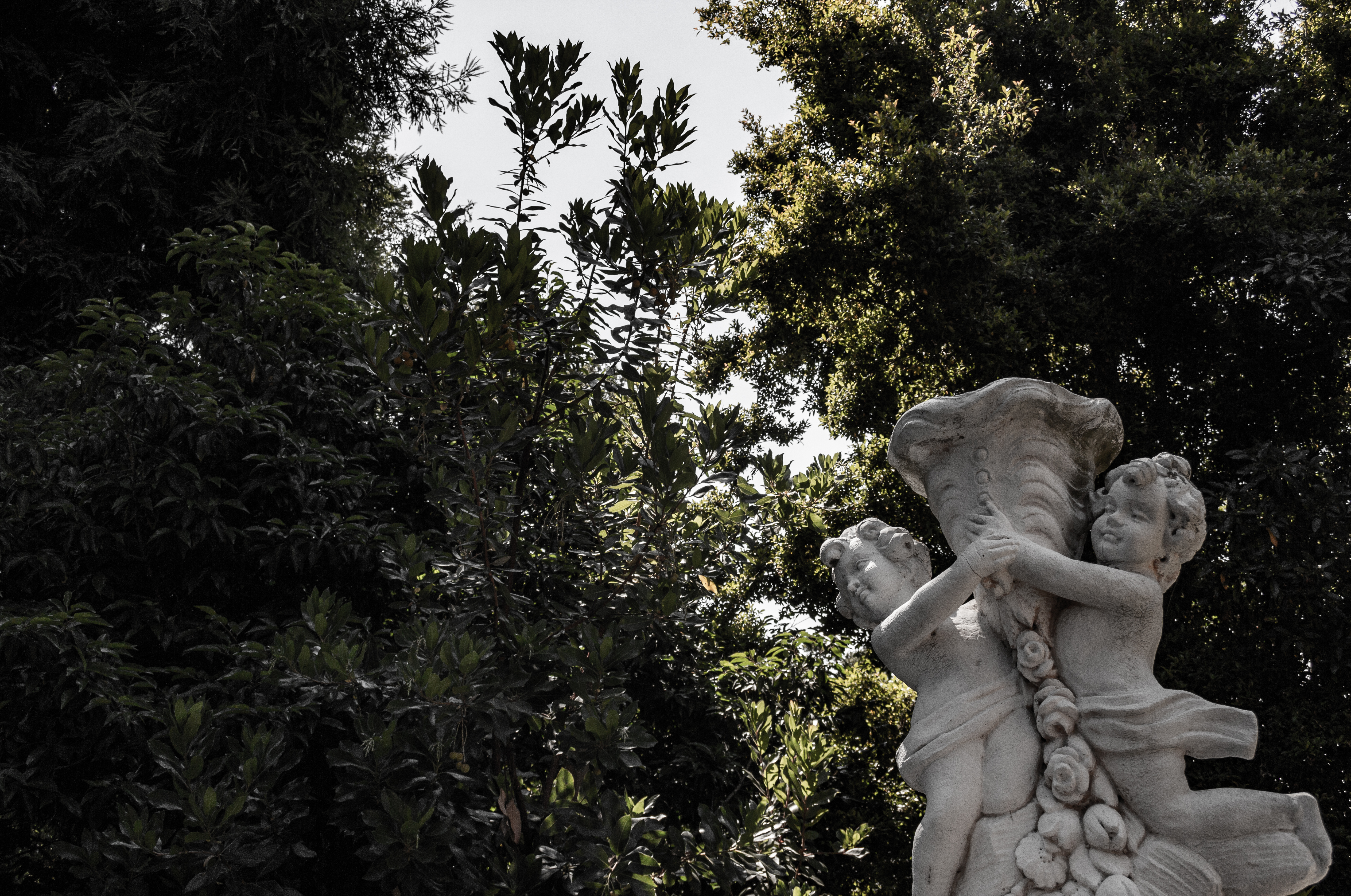 A photograph of a sculpture, with trees and sky in the background.