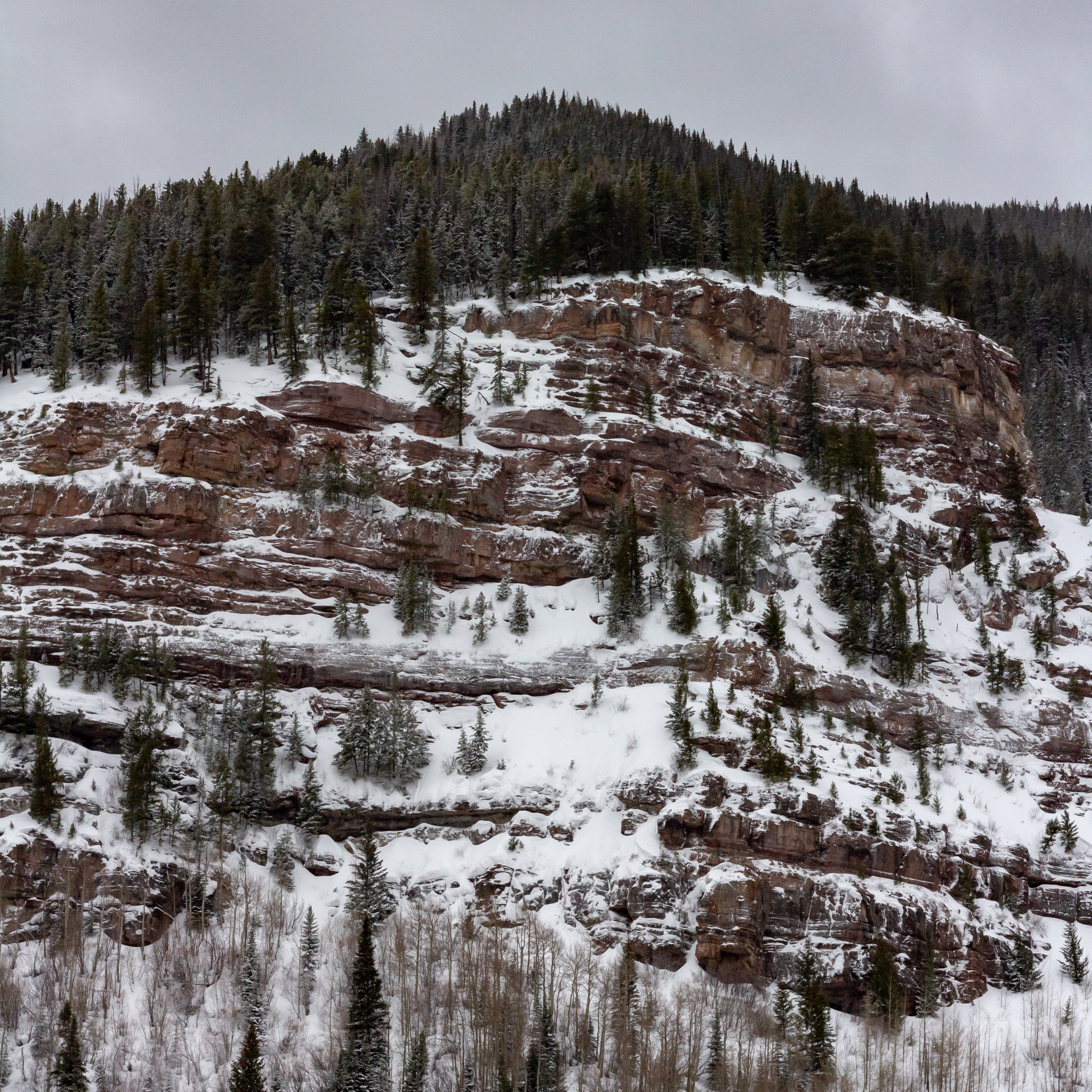 A photograph of a snowy cliff face, where you can clearly see the superposition of layers of rock.