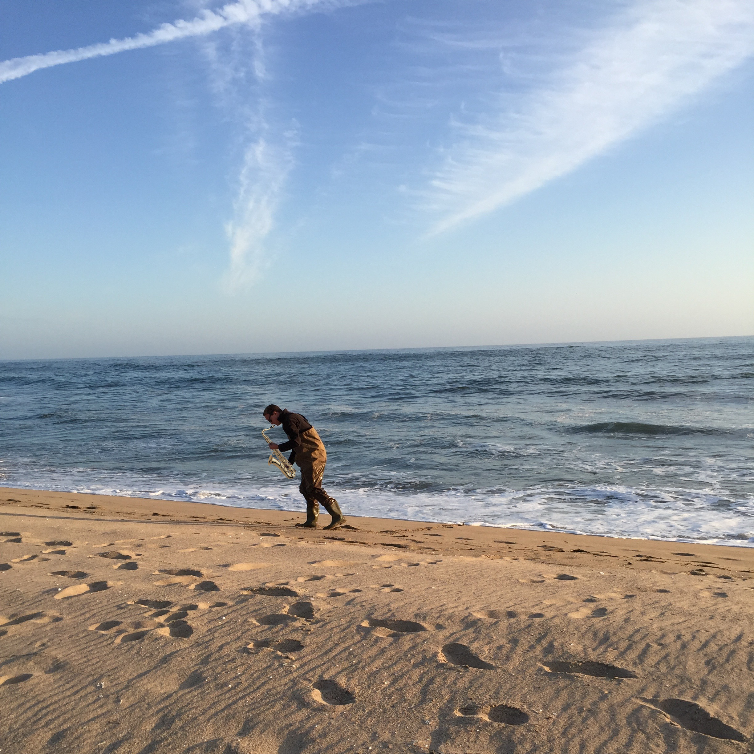 A digital image of a man playing saxaphone on the beach.
