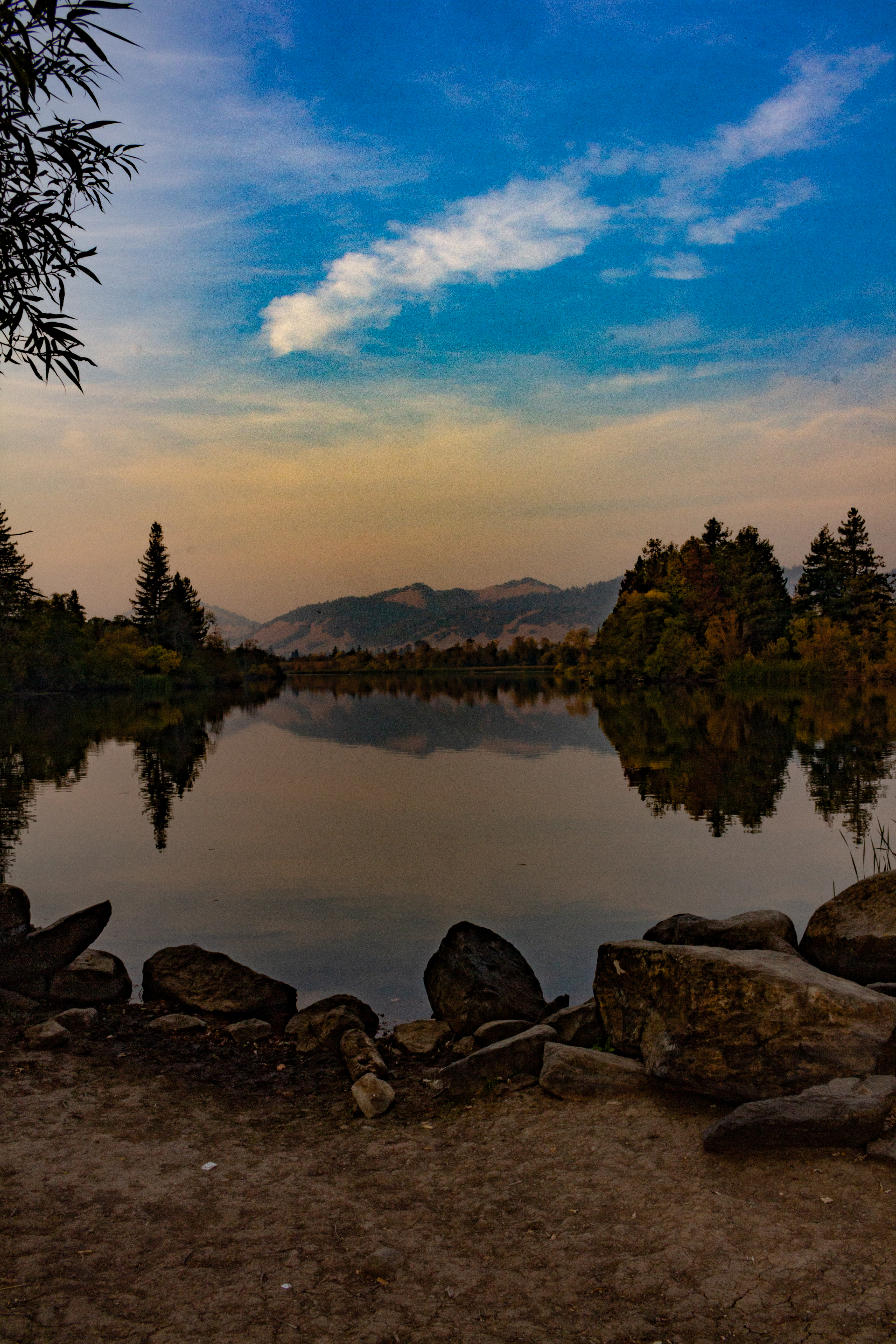 A photograph of the smog hovering over a mountain beyond a lake.