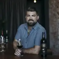 Headshot of Joe Wagner sitting at a table with a glass of wine.