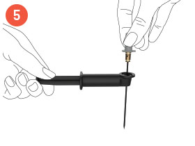 Manos insertando la aguja Coravin Model Eleven en el extremo de la herramienta de desobstrucción de agujas Model Eleven
