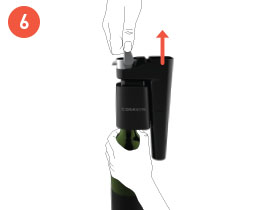 Una mano che tira il sistema Coravin Model Eleven verso l'altro dall'impugnatura e l'altra mano che mantiene la bottiglia in posizione
