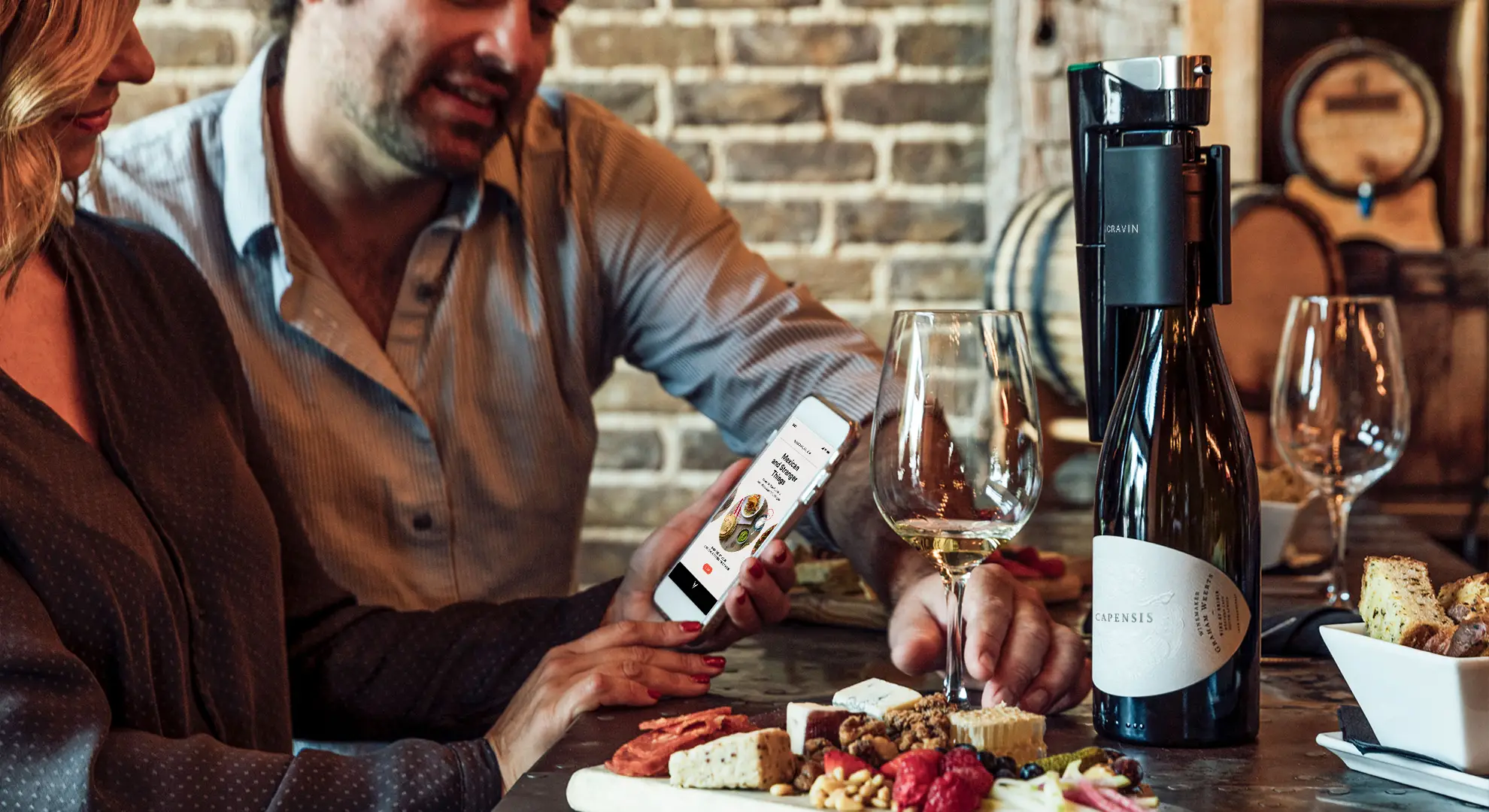 A couple using the Coravin Moments App at a restaurant, featuring the Coravin Model Eleven on bottle.