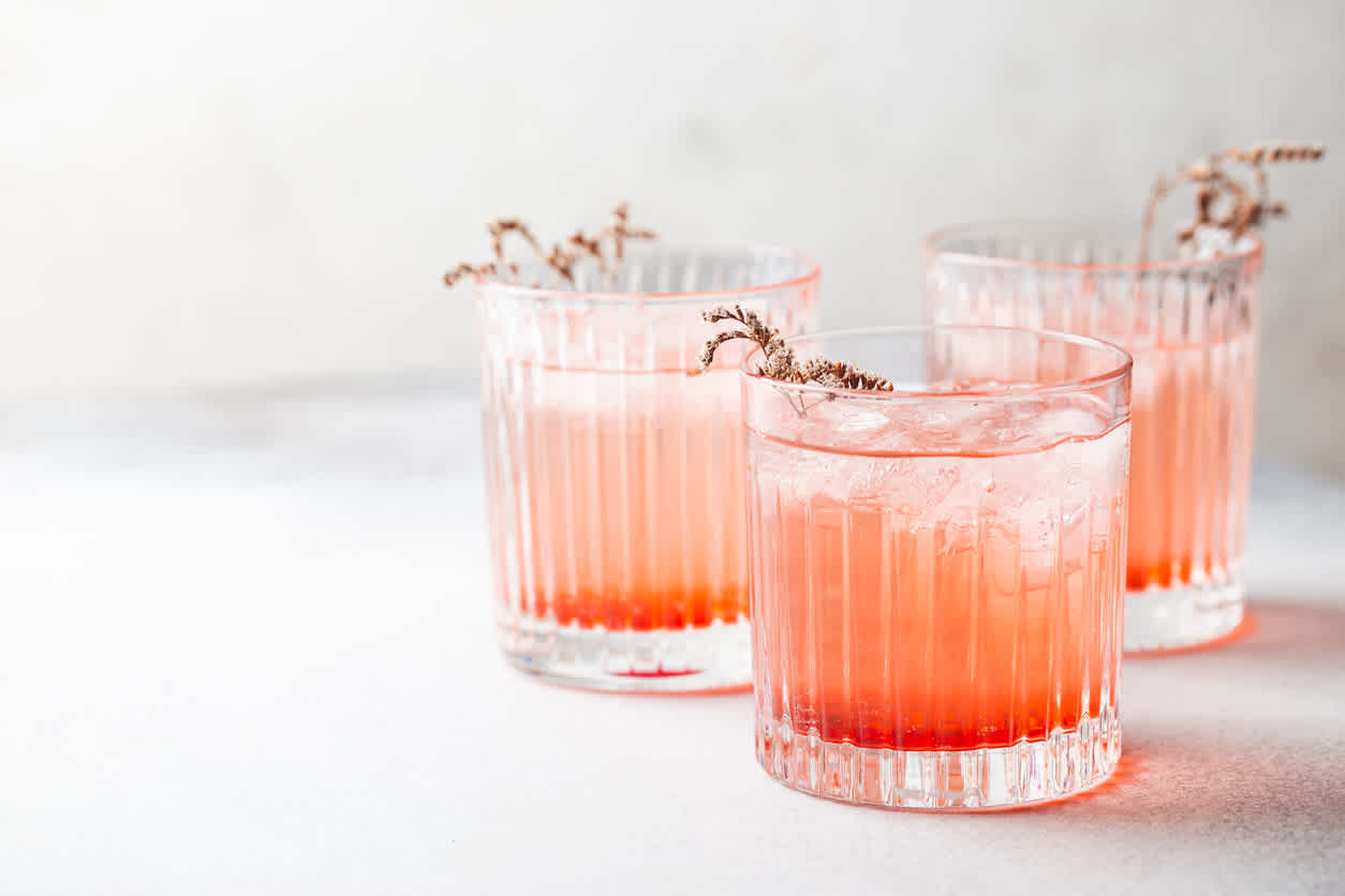 Three orange cocktails on a table.