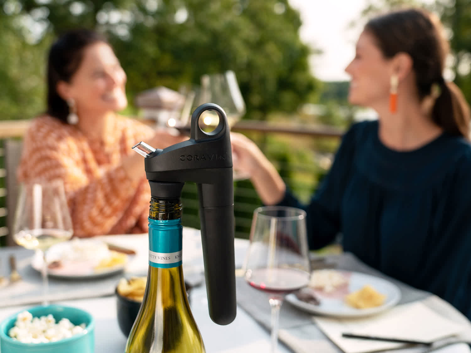 Pivot Wine Preservation System on bottle with women drinking wine and smiling in the background