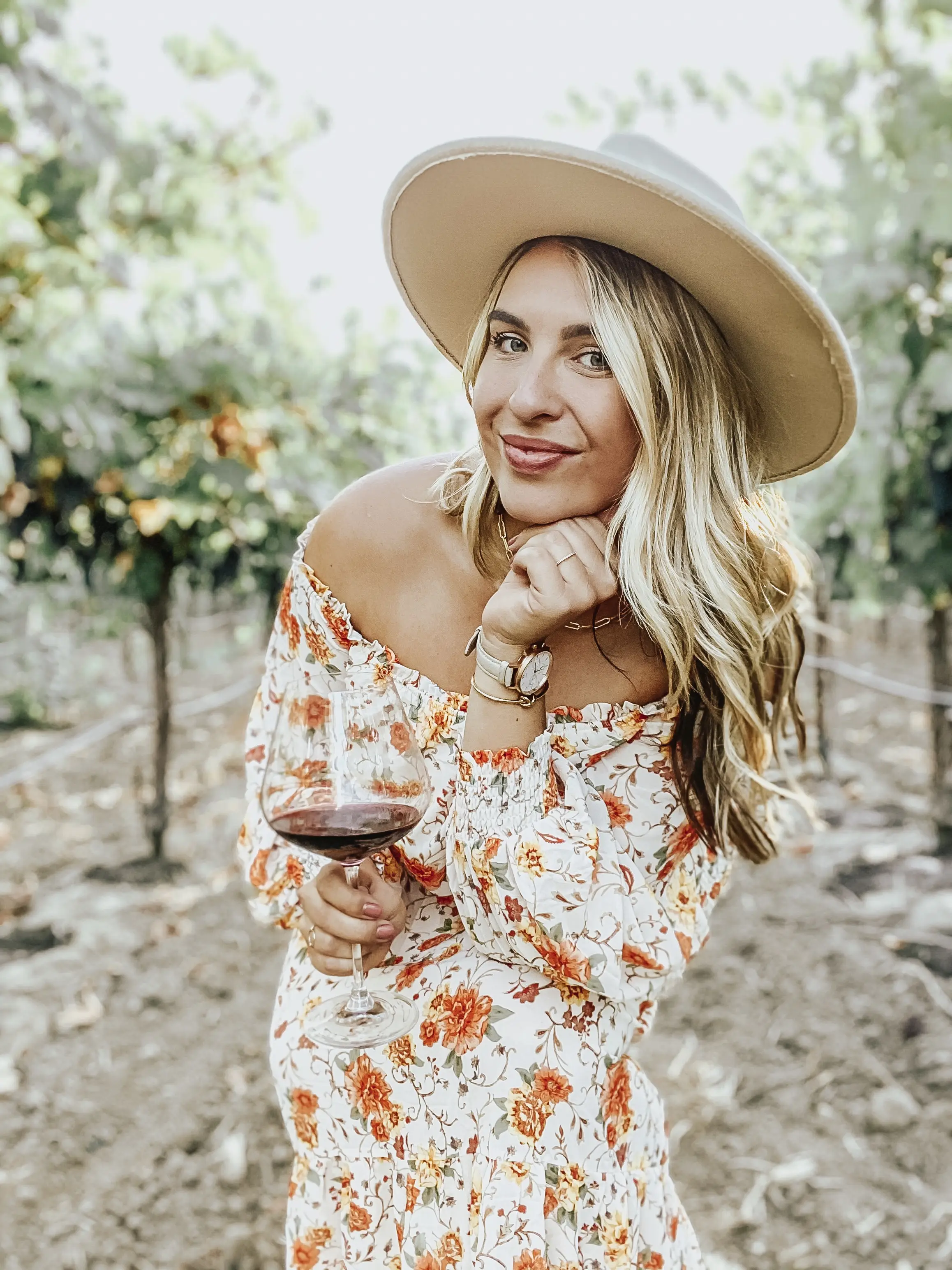 photo of raquel royers with hat on and wine in hand