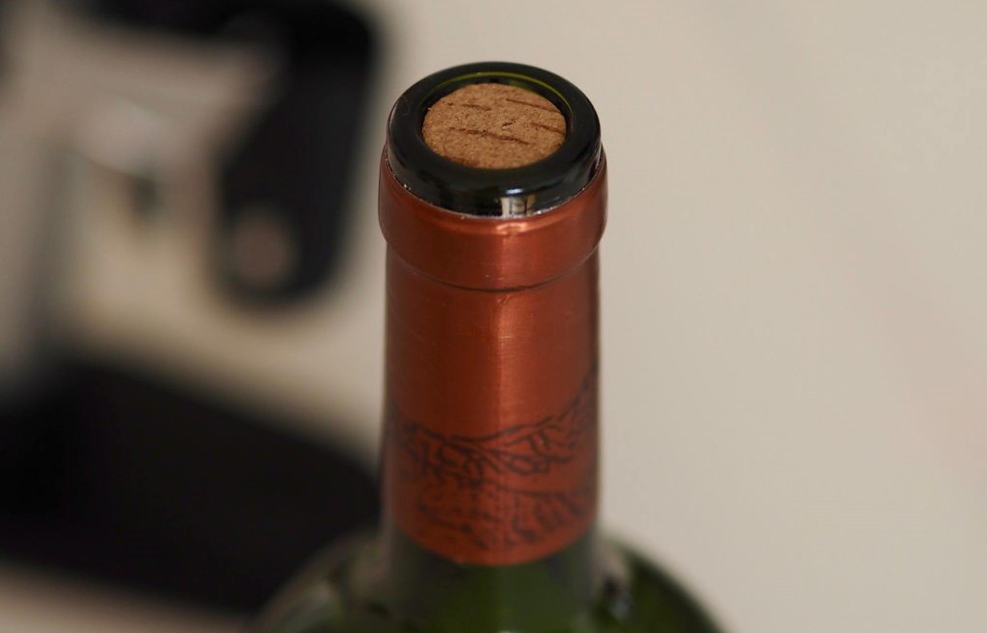 Close up image of the top of a wine bottle with cork still inserted.