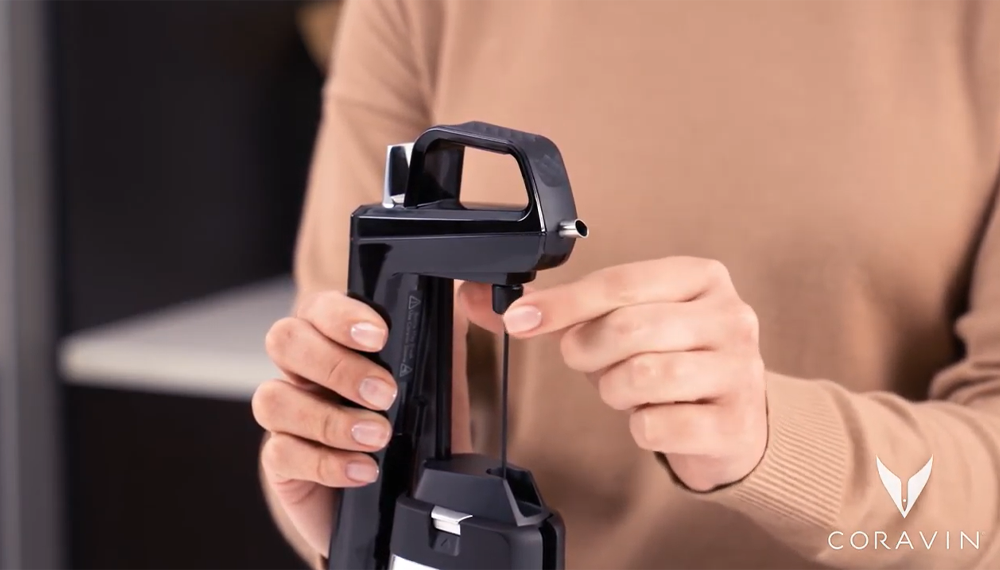 Woman screwing a Coravin needle into a Coravin Wine Preservation System. 