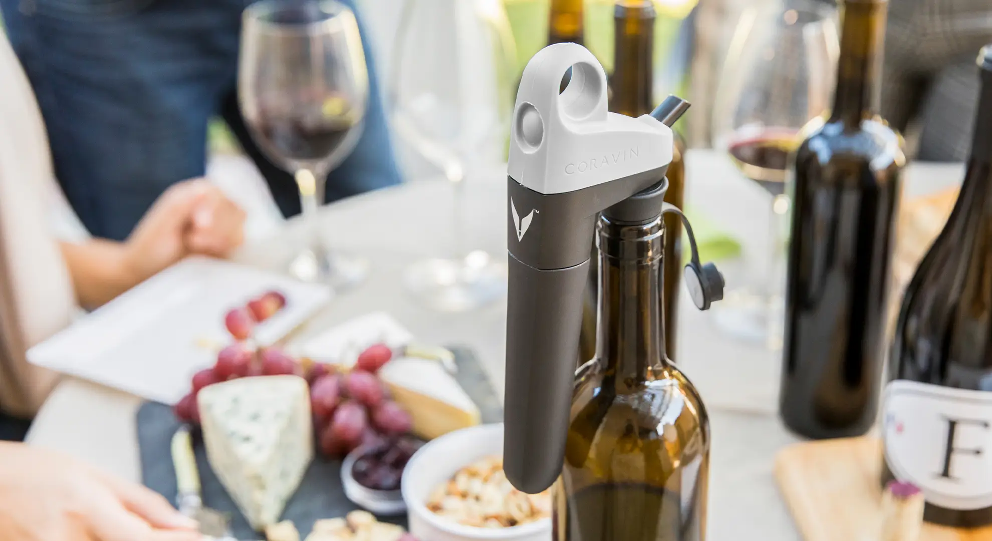 Pivot System on bottle, on a table with charcuterie and multiple wine bottles.