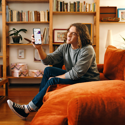 Joven mostrando la interfaz de Naranja X en su teléfono celular.