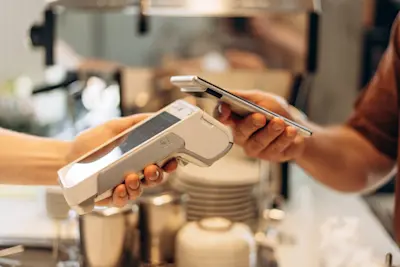 Cliente paga con el celular en una terminal de cobro de un bar
