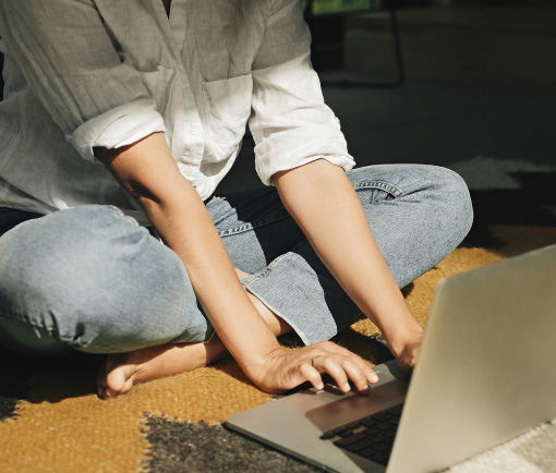Persona sentada sobre una alfombra usando una notebook