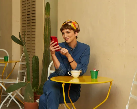 Mujer sentada en un café con su teléfono celular.