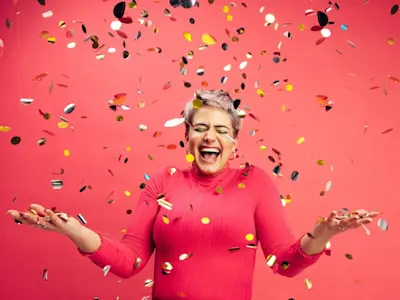 Mujer feliz bajo una lluvia de papel picado festeja la llegada del aguinaldo