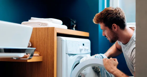 Hombre poniendo ropa a lavar en lavarropas