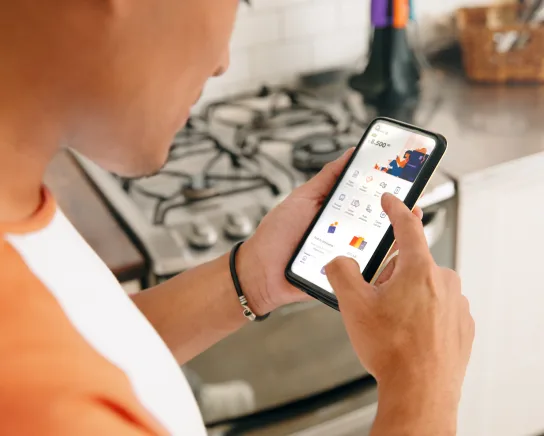 Hombre, en su cocina, usando la app de Naranja X.