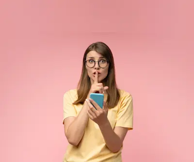 Mujer con anteojos hace gesto de silencio mientras sostiene el celular