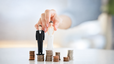 Muñecos de novios sobre pilas de monedas que representan el costo de casarse