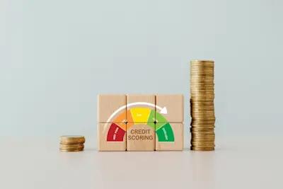 Bloques de madera con un medidor de puntaje crediticio entre pilas de monedas