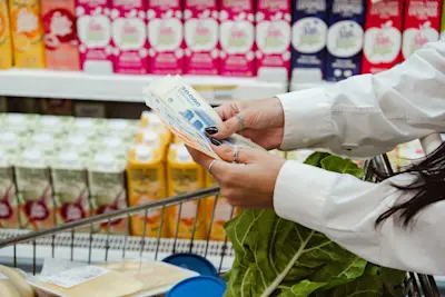 Mujer cuenta billetes frente a la góndola del supermercado