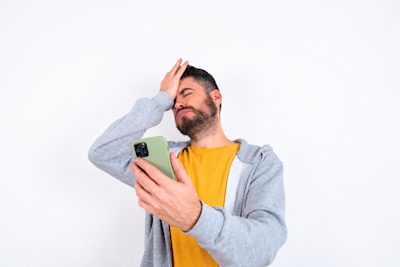 Hombre se lleva la mano a la frente mientras mira el celular