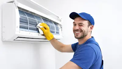 Técnico sonriente limpia el filtro de un aire acondicionado