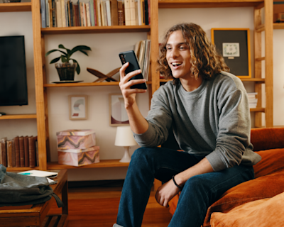 Joven usando su teléfono celular en el living.