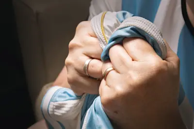 Manos aprietan con fuerza una camiseta celeste y blanca