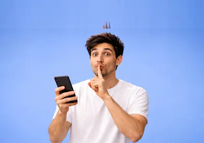 Hombre con el celular en la mano hace gesto de silencio