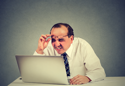 Hombre con anteojos achina los ojos frente a la pantalla de una notebook